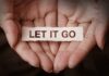 Two hands gently holding a piece of paper with the words "let it go" written on it, symbolizing the journey of releasing stress or moving on from past troubles.