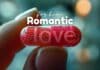 A hand holding a capsule with red beads inside, the word "love" inscribed on it. The background is blurred with bokeh lights, and the text "Romantic-Gestures-for-Him" is written above the capsule.