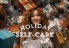 A woman with curly hair is smiling and surrounded by numerous wrapped gifts. The text "HOLIDAY SELF-CARE" is overlaid on the image, emphasizing self-care-during-the-holidays. The gifts are wrapped in festive paper with various colors, including gold, blue, and white. The scenery exudes a cheerful holiday atmosphere.